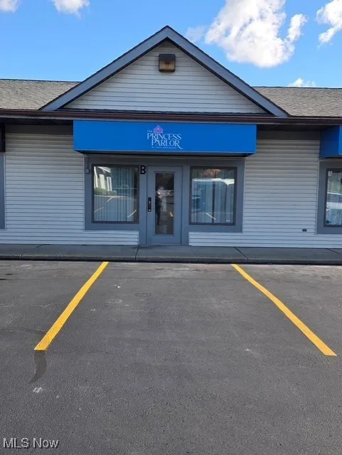 Doorway to property featuring roof with shingles and uncovered parking
