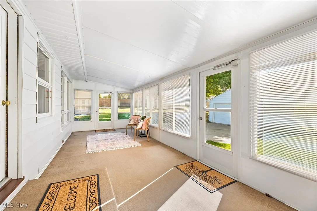 Enclosed porch with carpet, plenty of natural light, and lofted ceiling