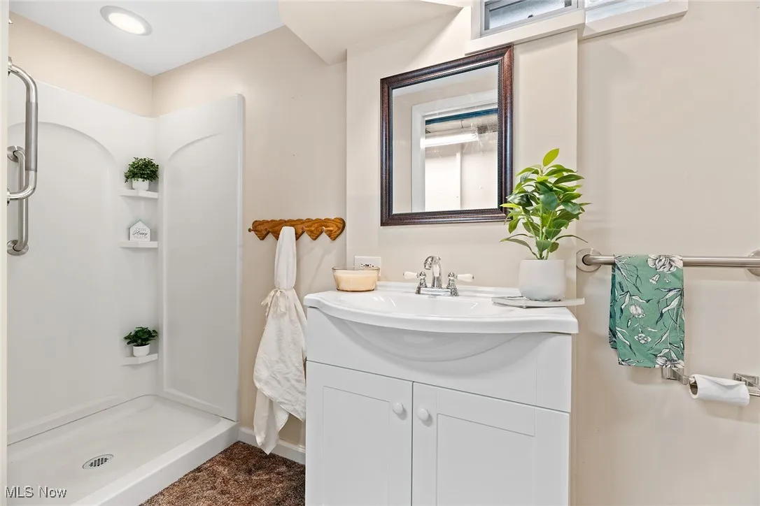 Full bathroom n the basement featuring a stall shower and vanity
