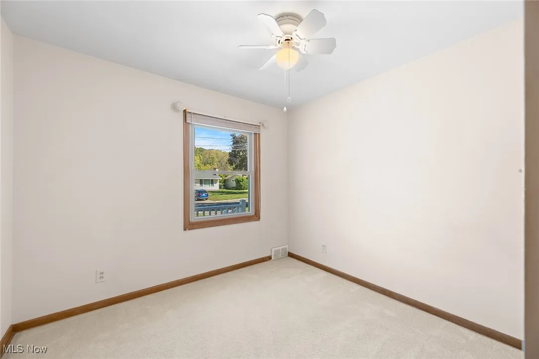 Carpeted empty room with baseboards and ceiling fan
