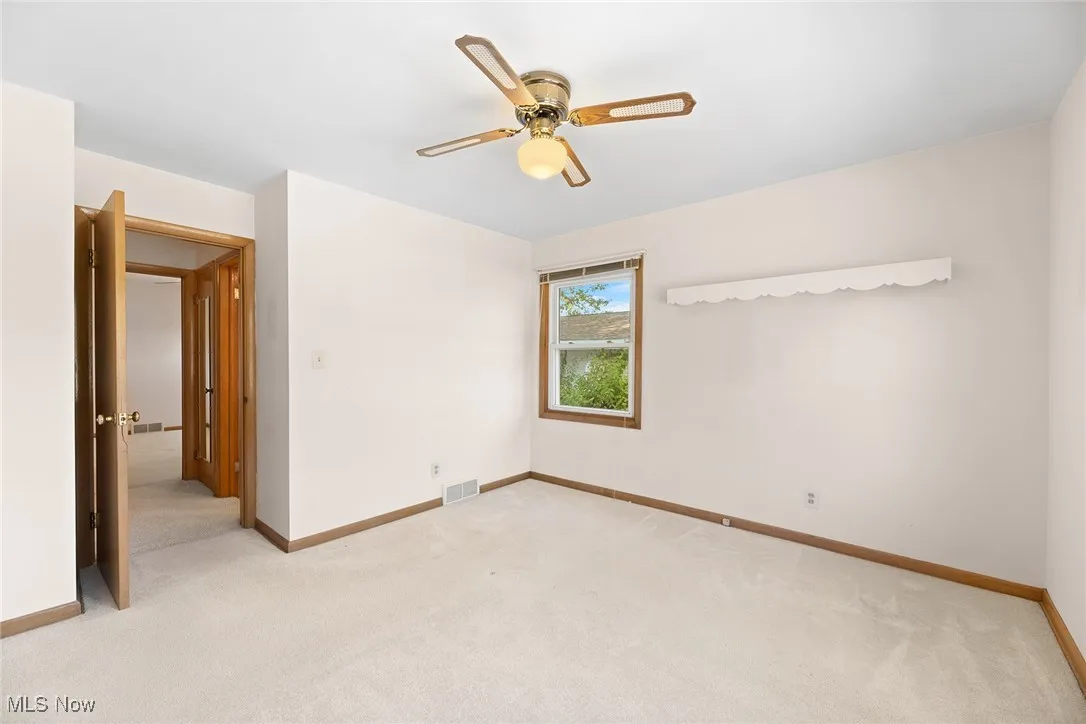 Unfurnished room featuring light colored carpet and a ceiling fan