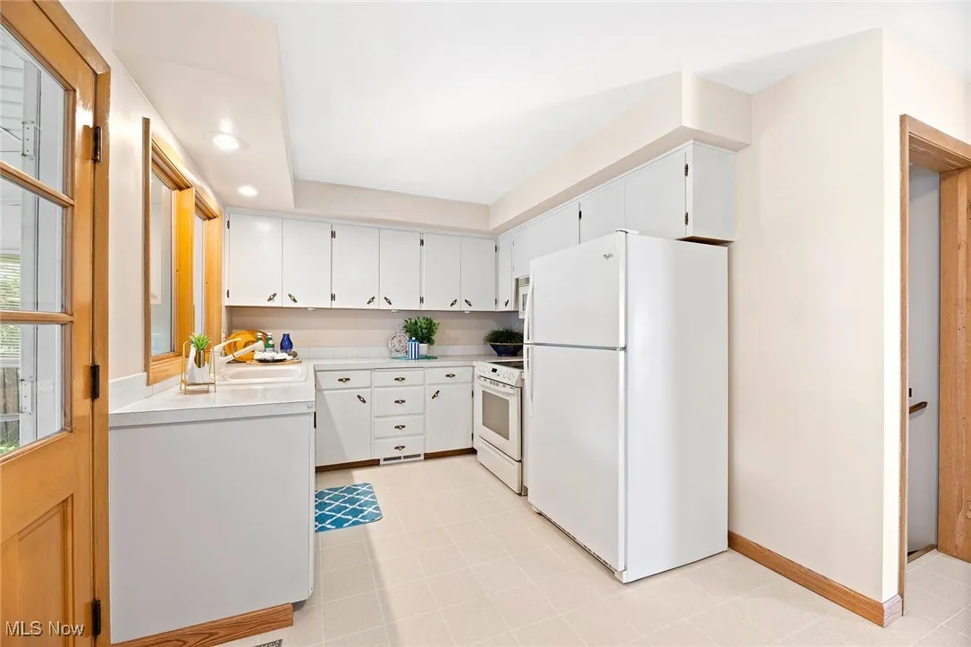 Kitchen featuring white appliances, light countertops, white cabinets, recessed lighting, and light tile patterned flooring