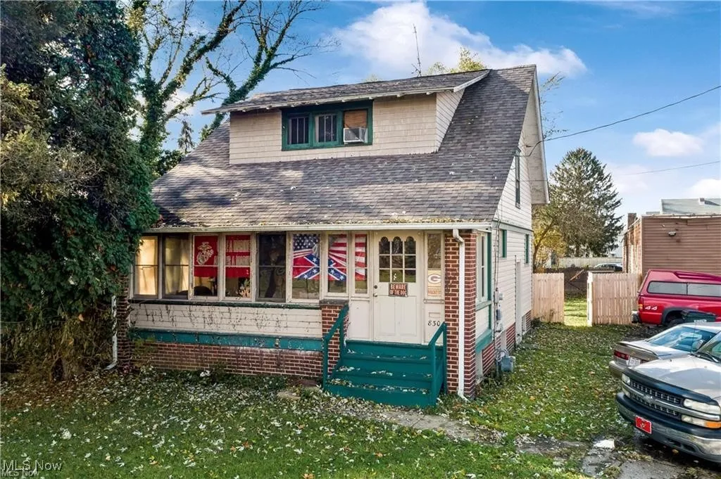 View of front facade featuring a shingled roof and brick siding