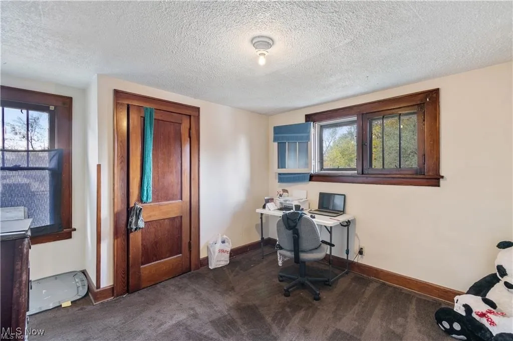 Home office with a textured ceiling and dark carpet