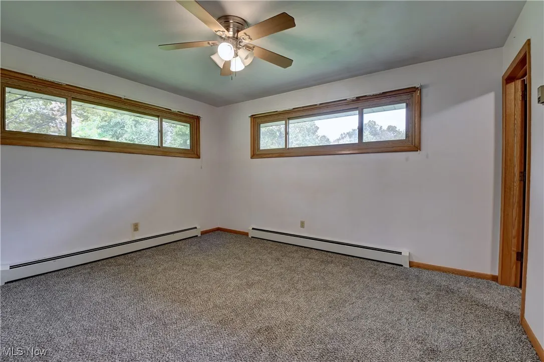Unfurnished bedroom featuring baseboard heating, carpet floors, and ceiling fan