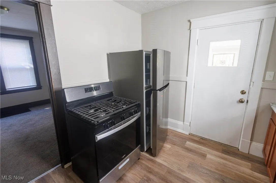 Kitchen featuring gas range, light wood-type flooring, a textured ceiling, and light countertops