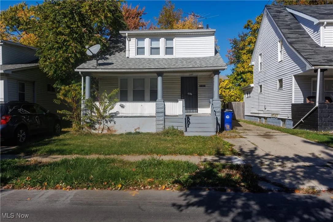 Bungalow-style home with a porch, a shingled roof, and a front yard