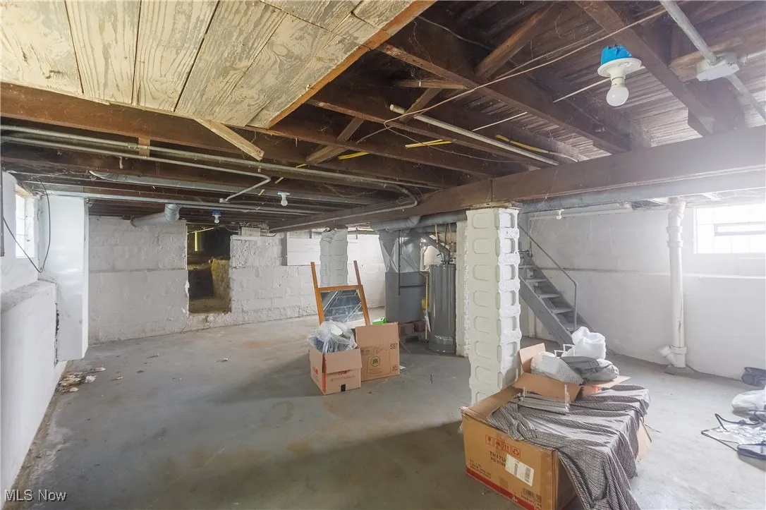 Basement featuring stairway, water heater, and heating unit