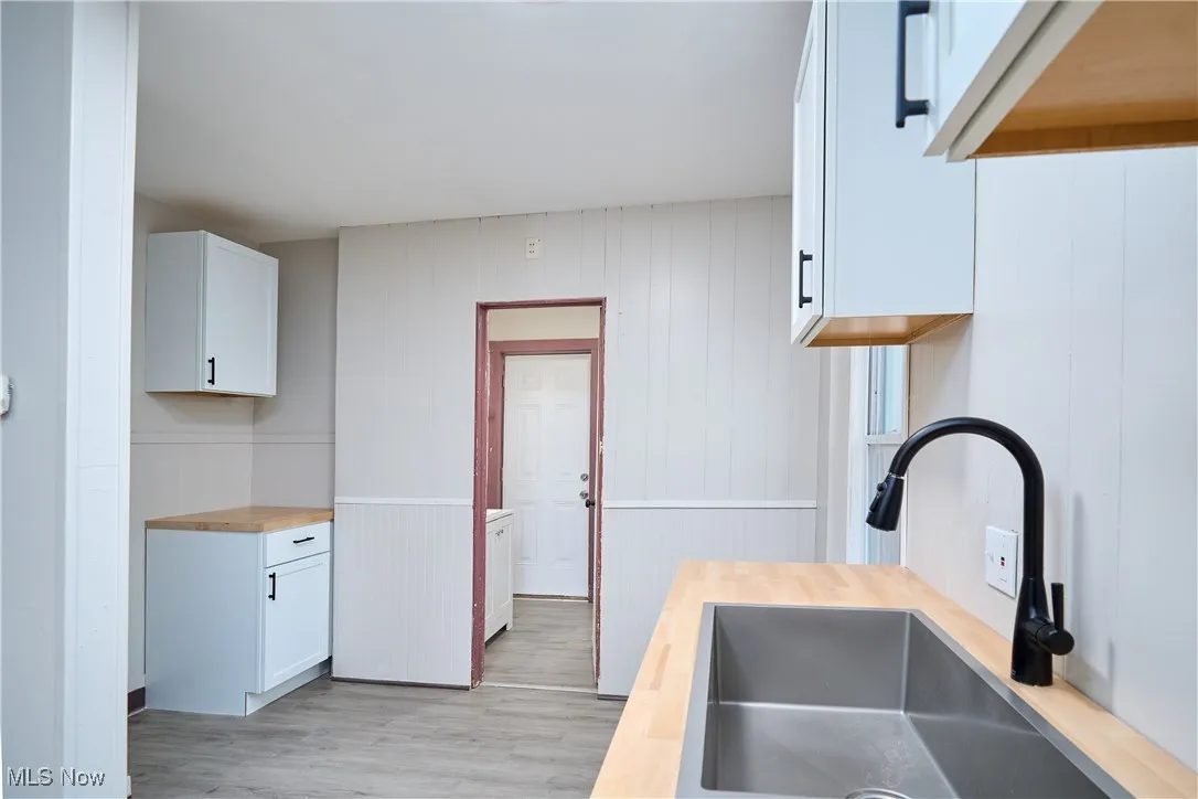 Kitchen with wooden counters, white cabinets, and light wood-style flooring