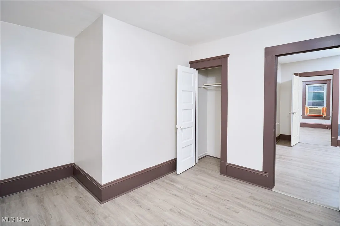 Unfurnished bedroom with light wood finished floors, a closet, and cooling unit