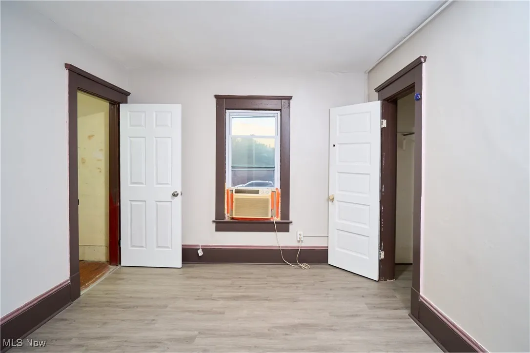 Unfurnished bedroom with light wood-type flooring and cooling unit
