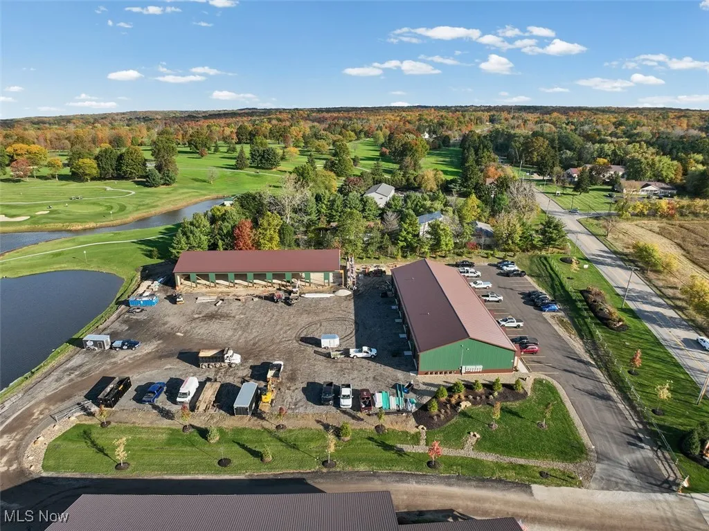 Aerial view of property's location with a golf course and a nearby body of water
