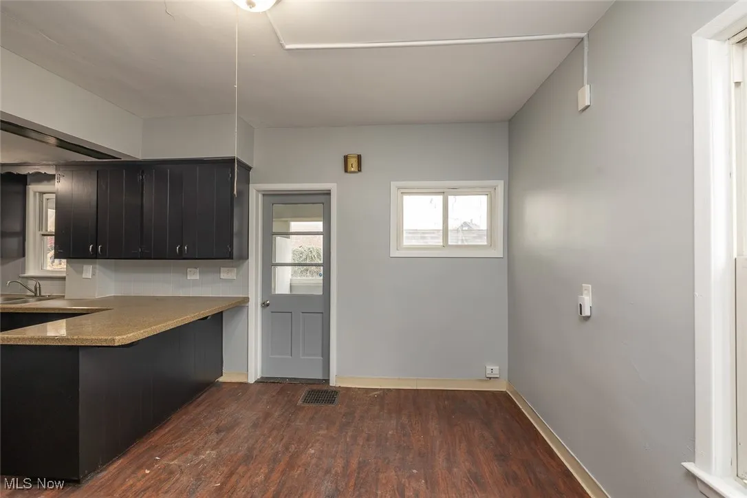 Kitchen featuring dark cabinets, dark wood-style flooring, and a peninsula