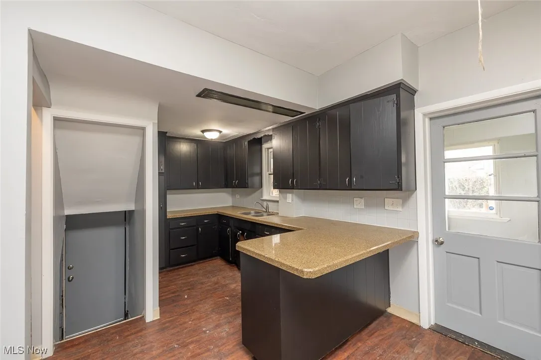 Kitchen featuring dark cabinets, dark wood-type flooring, and a peninsula