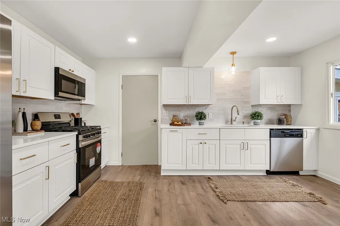 Kitchen with white cabinets, appliances with stainless steel finishes, decorative backsplash, and recessed lighting