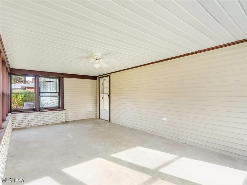 Unfurnished sunroom with ceiling fan and a patio area