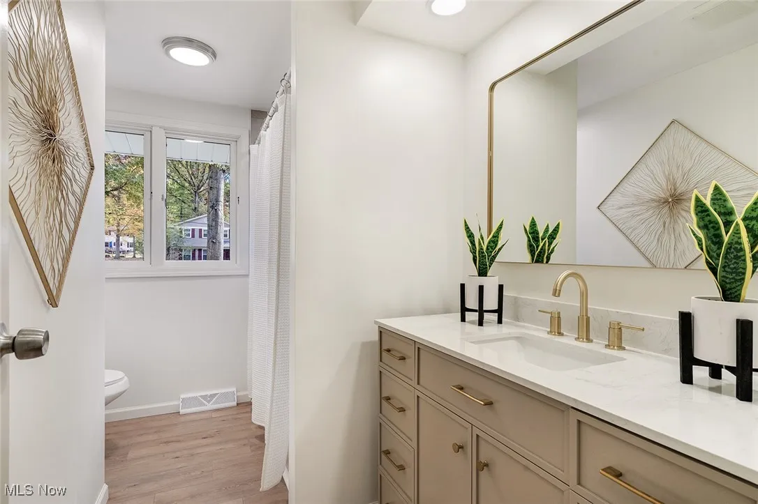 Bathroom with vanity, a shower with curtain, and light wood finished floors