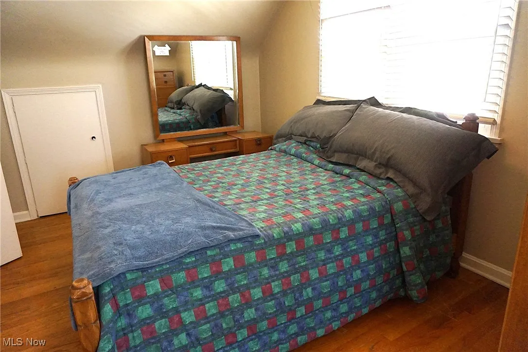 Bedroom 2 view 3 featuring wood floors and vaulted ceiling.