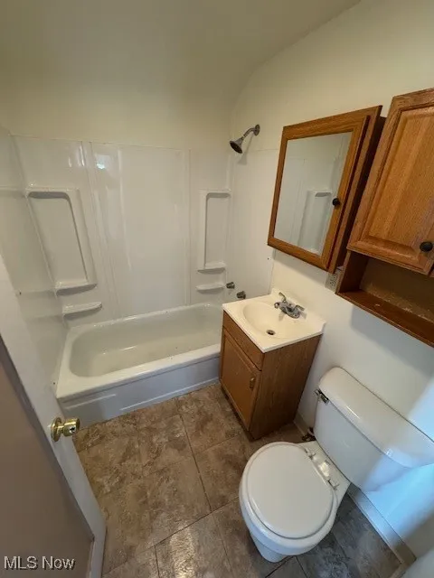 Full bath featuring vanity, shower / bath combination, and dark tile patterned flooring