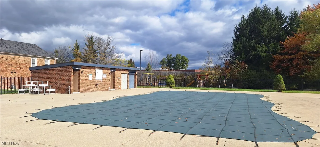 Community pool featuring a fenced backyard, a playground, and an outdoor structure