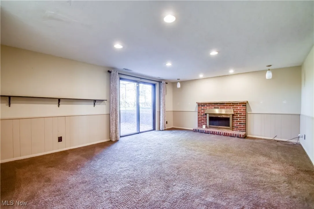 Unfurnished living room featuring a fireplace, a wainscoted wall, recessed lighting, and carpet flooring