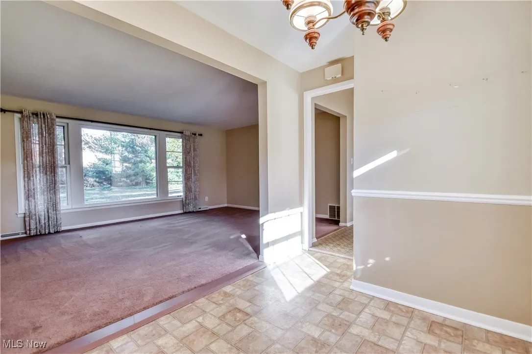 Spare room featuring light colored carpet and a chandelier