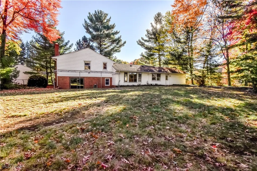 Rear view of house featuring a chimney, a yard, and brick siding