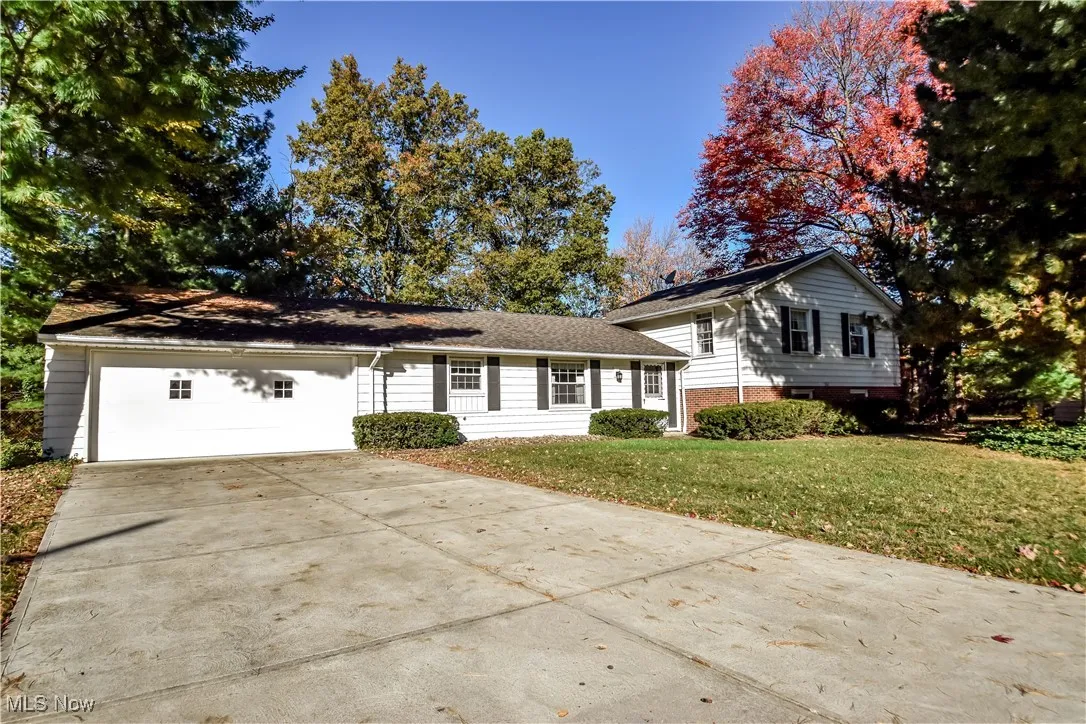 Split level home featuring driveway, a front lawn, brick siding, and a garage