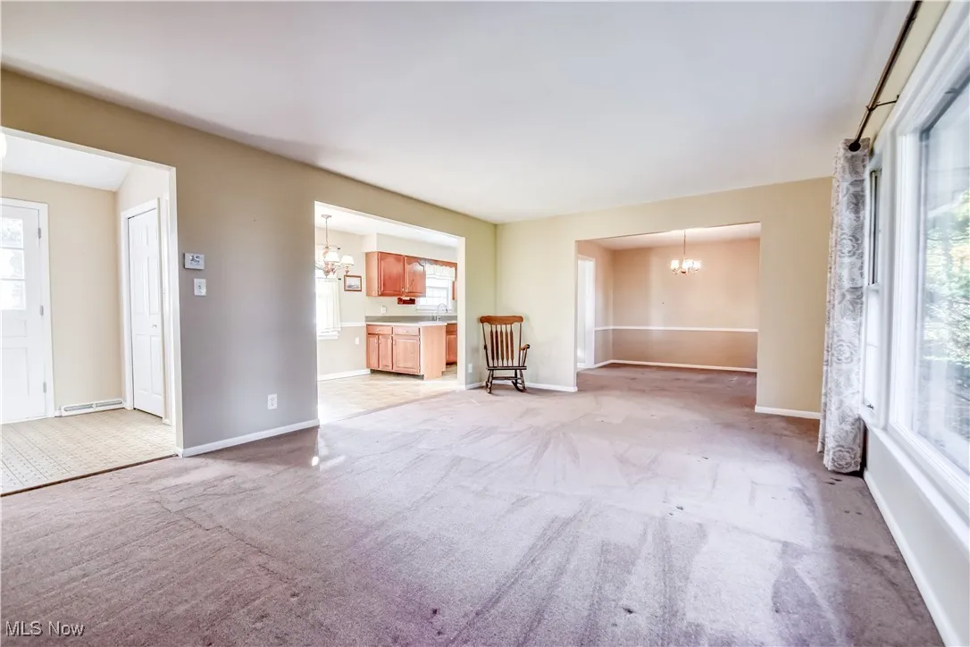 Unfurnished living room featuring a chandelier and light carpet