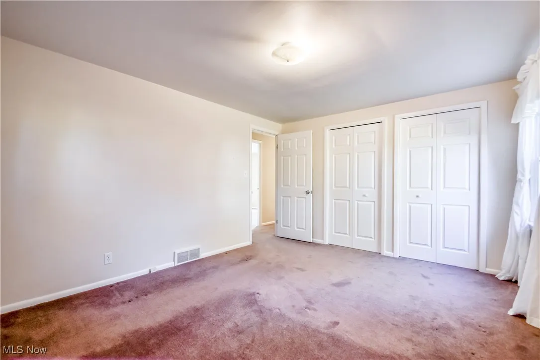 Unfurnished bedroom featuring two closets and carpet flooring