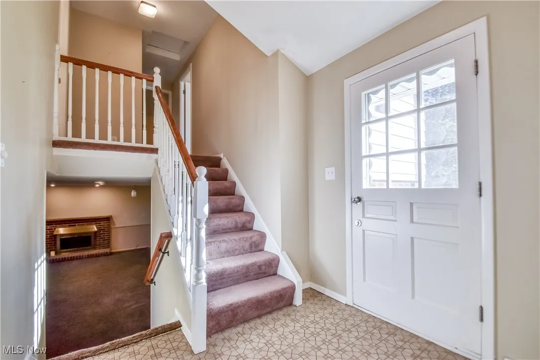 Foyer entrance featuring a fireplace and light colored carpet