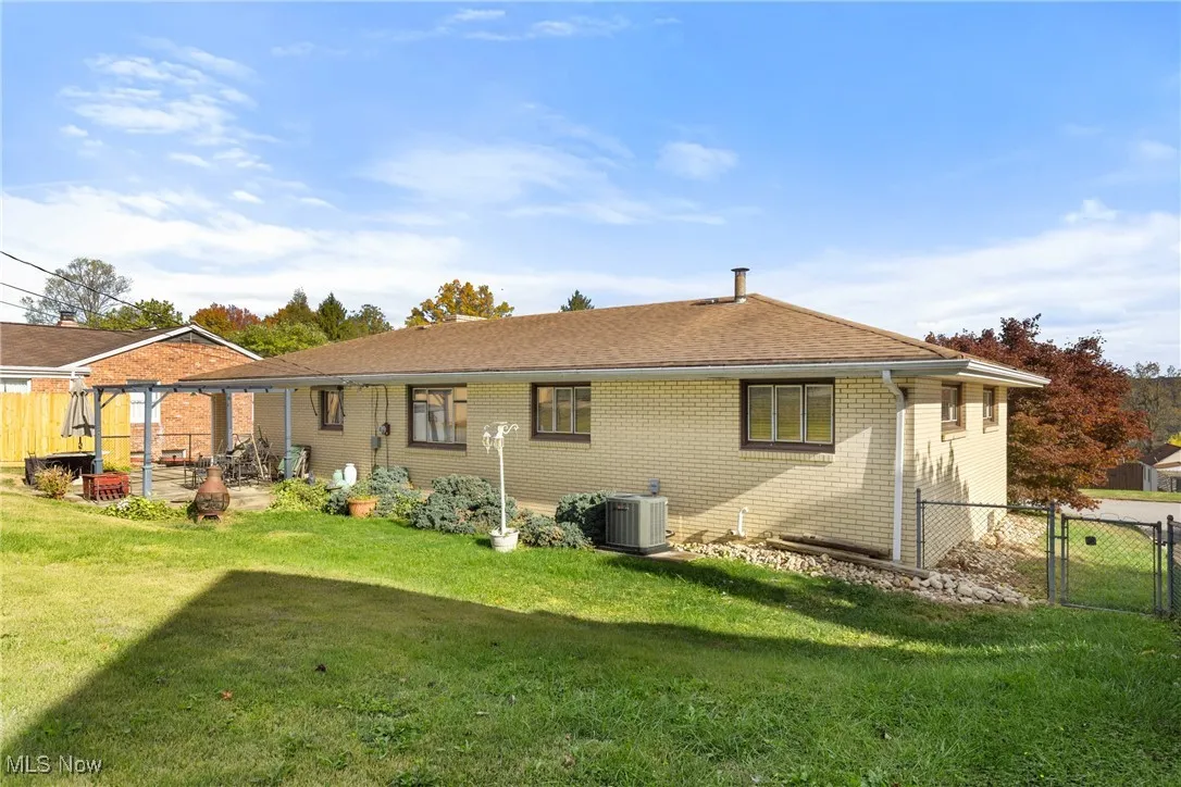 Rear view of house featuring a gate, brick siding, and a patio