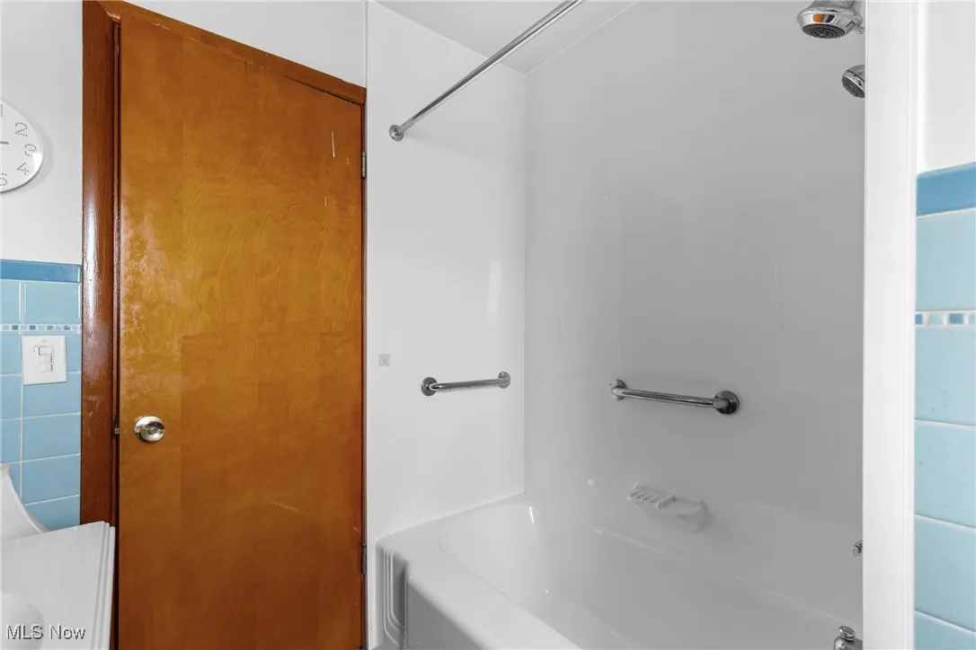 Full bath with shower / tub combination, tile walls, and vanity