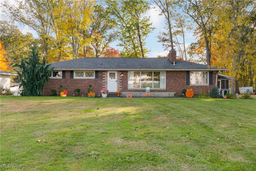 Ranch-style house featuring a front lawn, a chimney, and brick siding