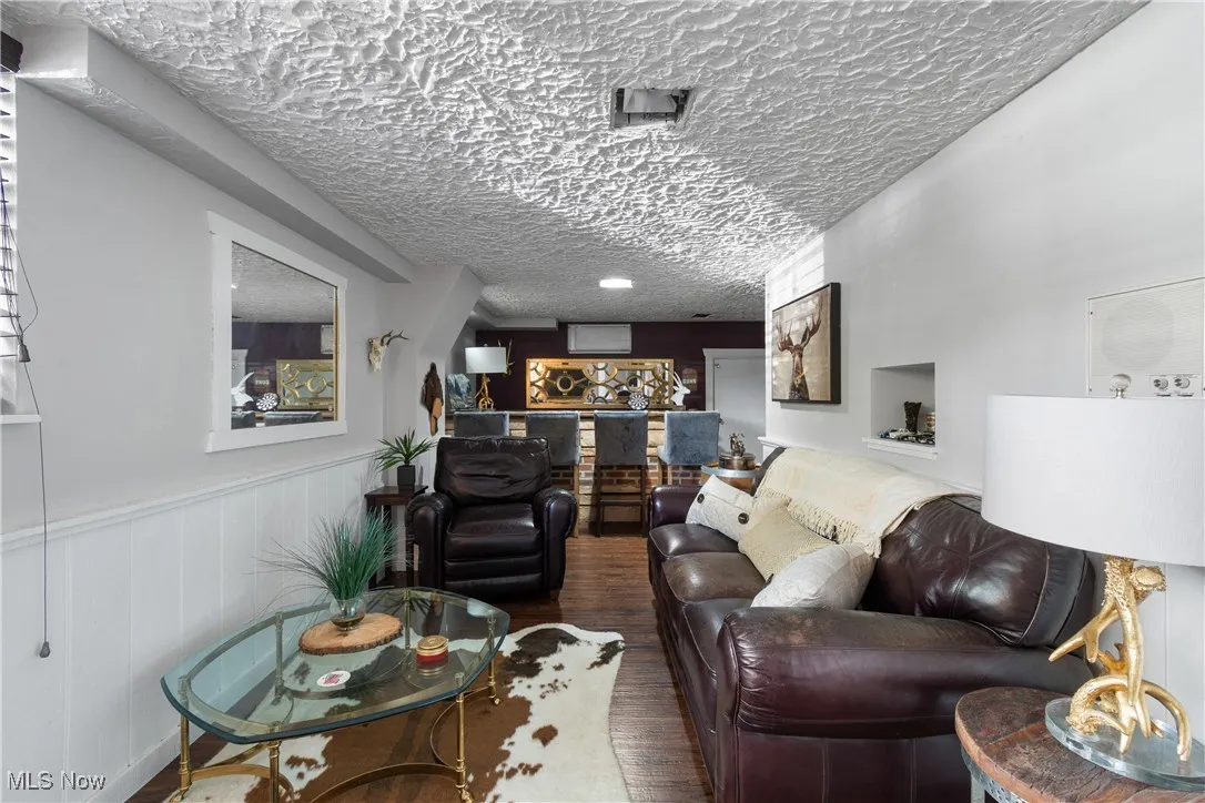 Living area featuring a textured ceiling, wainscoting, and wood finished floors