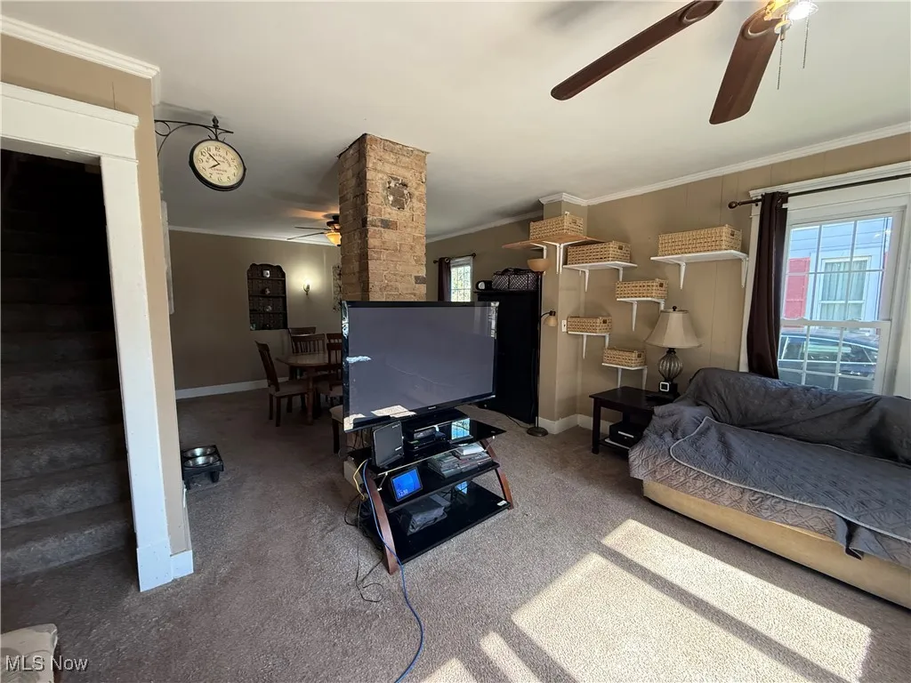 Carpeted living area with ceiling fan
