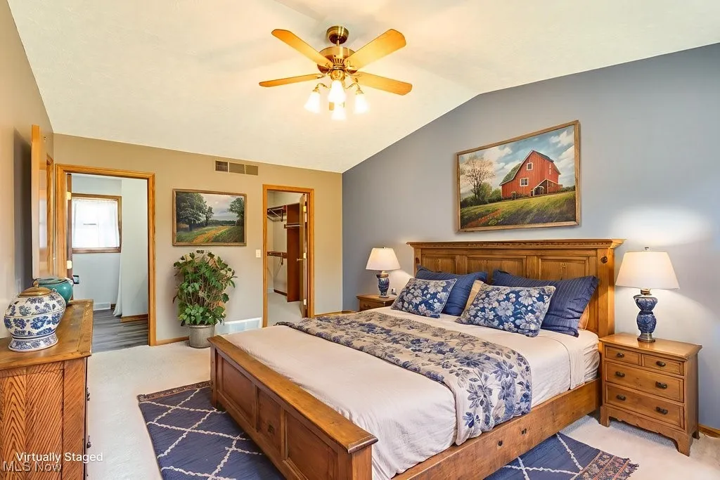 Bedroom featuring lofted ceiling, a ceiling fan, and ensuite bath