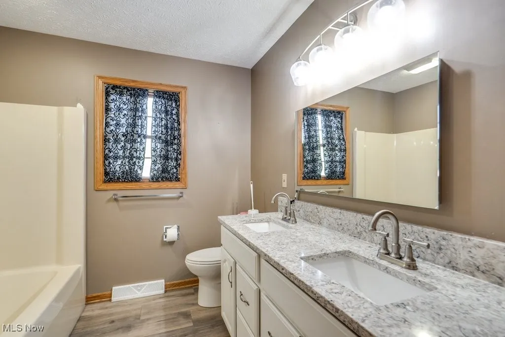 Kitchen featuring a kitchen breakfast bar, a center island, decorative backsplash, white cabinets, and a textured ceiling