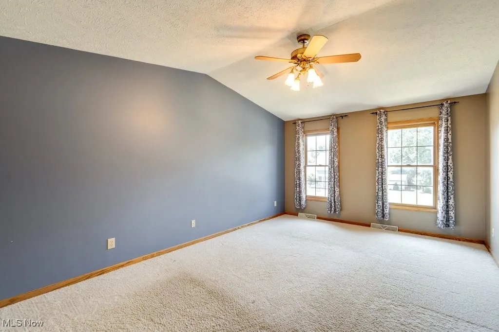 Unfurnished bedroom with a spacious closet, lofted ceiling, ceiling fan, and carpet floors