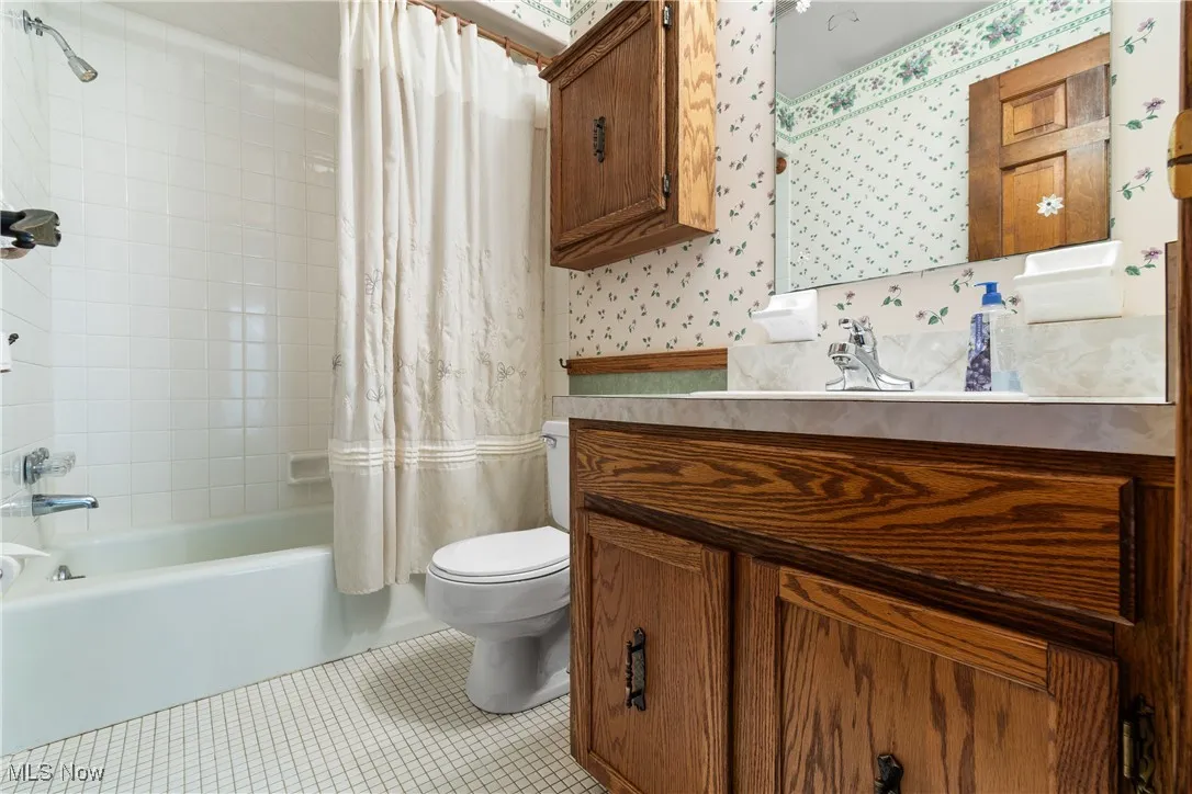 Bathroom featuring wallpapered walls, vanity, shower / bath combo, and tile patterned flooring