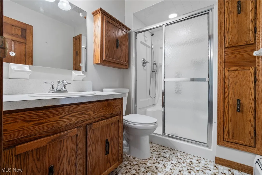 Full bath with vanity, a shower stall, and light tile patterned floors