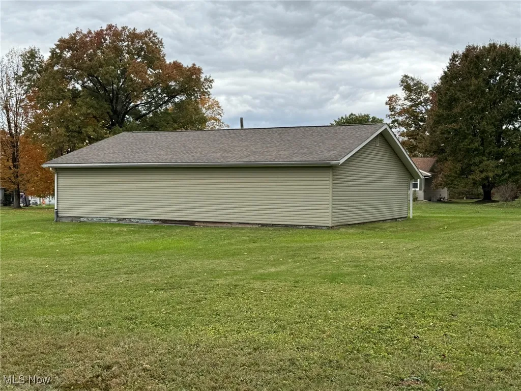 View of side of property featuring a yard and a shingled roof
