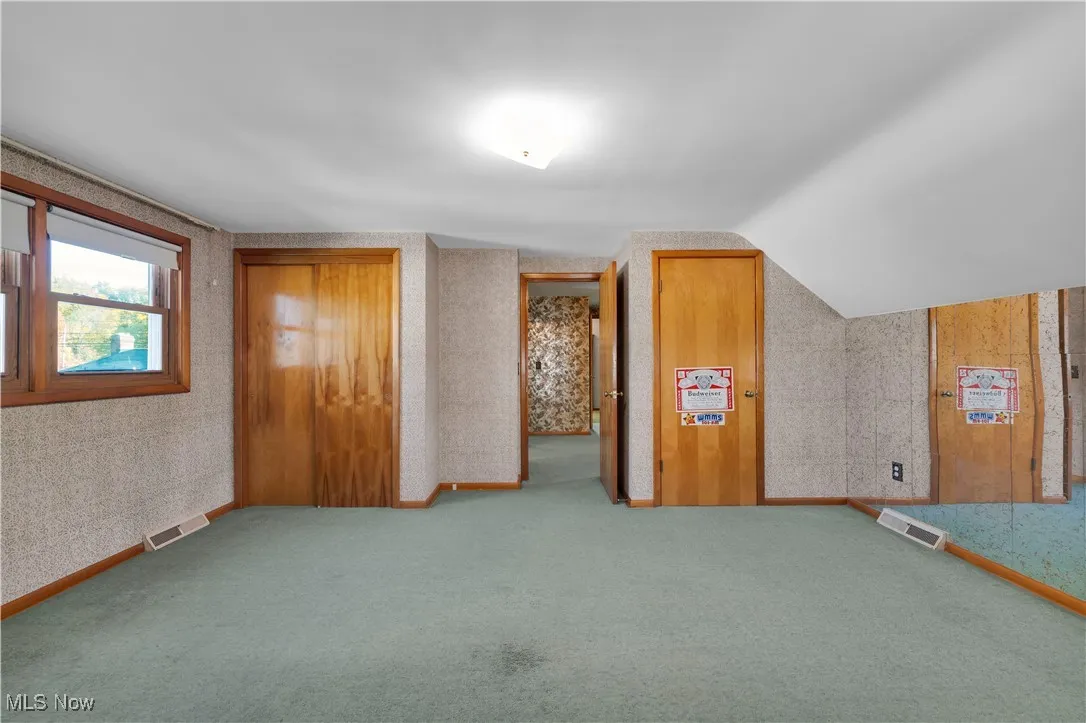 Additional living space featuring wallpapered walls and carpet flooring