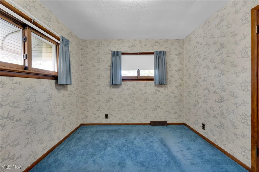 Unfurnished room with wallpapered walls and carpet