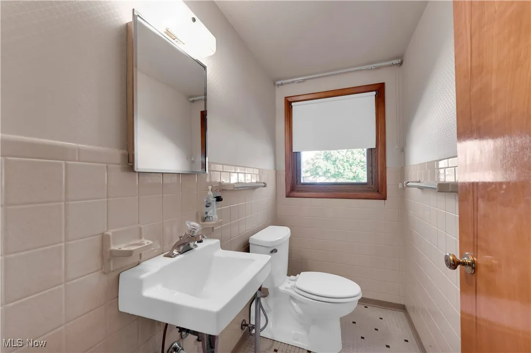 Bathroom with tile walls, tile patterned floors, and wainscoting