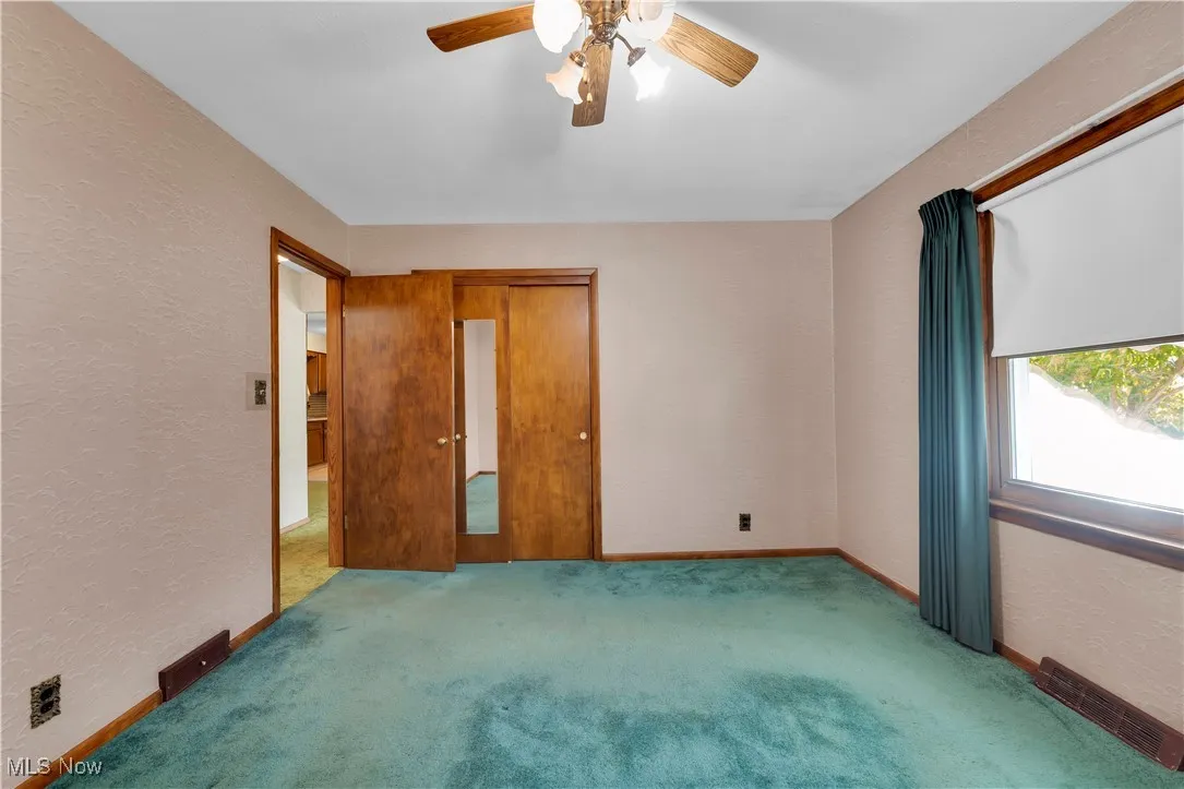 Unfurnished bedroom featuring a textured wall, a ceiling fan, and carpet flooring