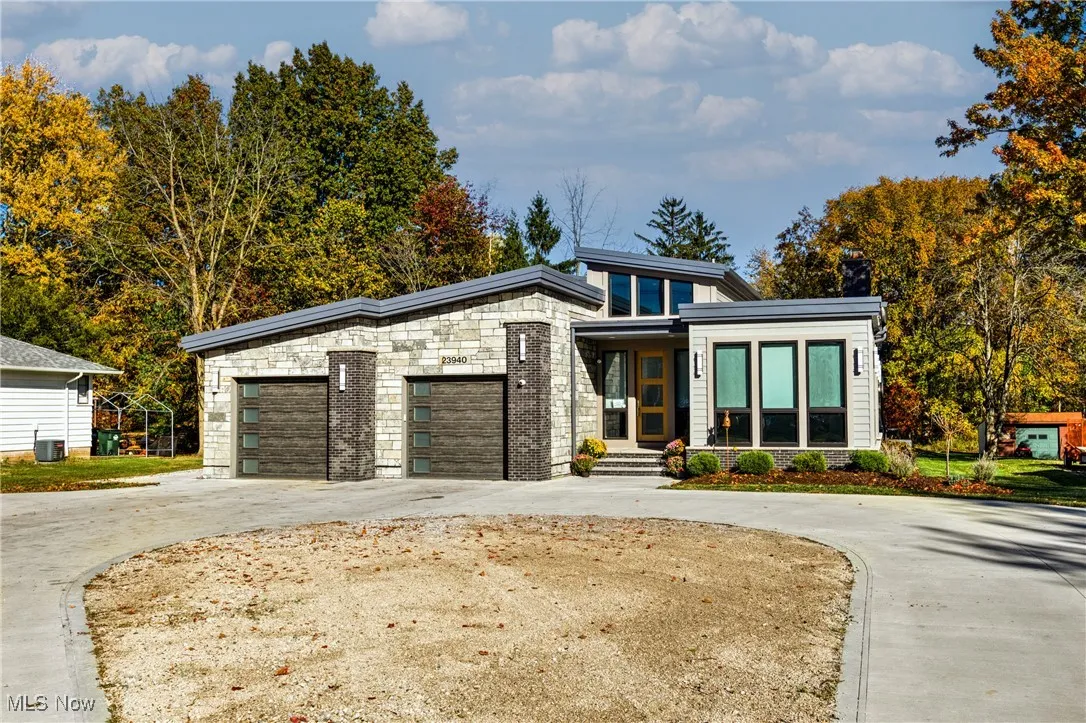 Modern home featuring driveway, stone siding, and a garage