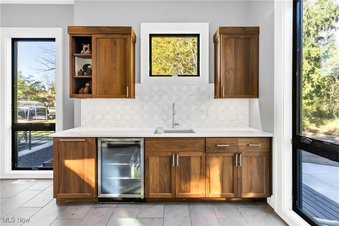 Bar featuring healthy amount of natural light, backsplash, and wine cooler