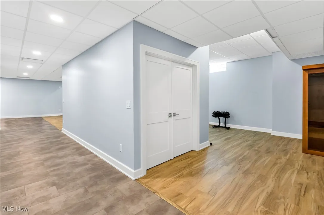 Finished basement featuring a paneled ceiling and light wood-style flooring