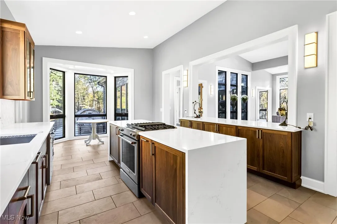 Kitchen with gas stove, light stone countertops, brown cabinets, recessed lighting, and a center island
